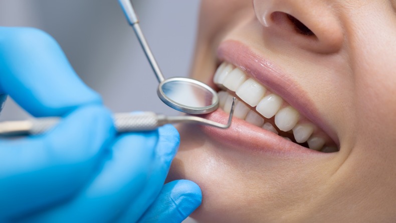 Mulher sorrindo enquanto dentista trata seus dentes